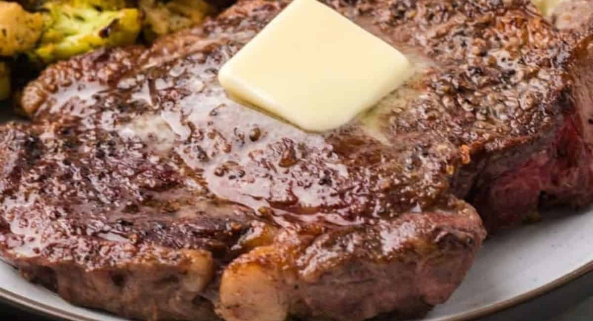 Up close image of chuck eye steak with slice of butter.