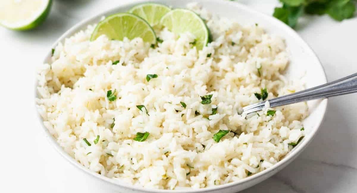Overhead image of cilantro lime rice in a white bowl with a silver spoon.