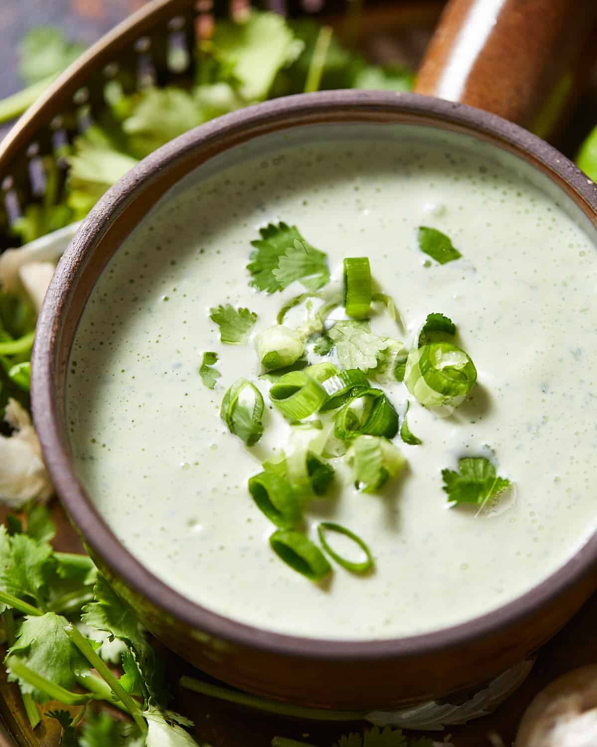 3/4 angle shot of cilantro garlic sauce in a brown bowl.