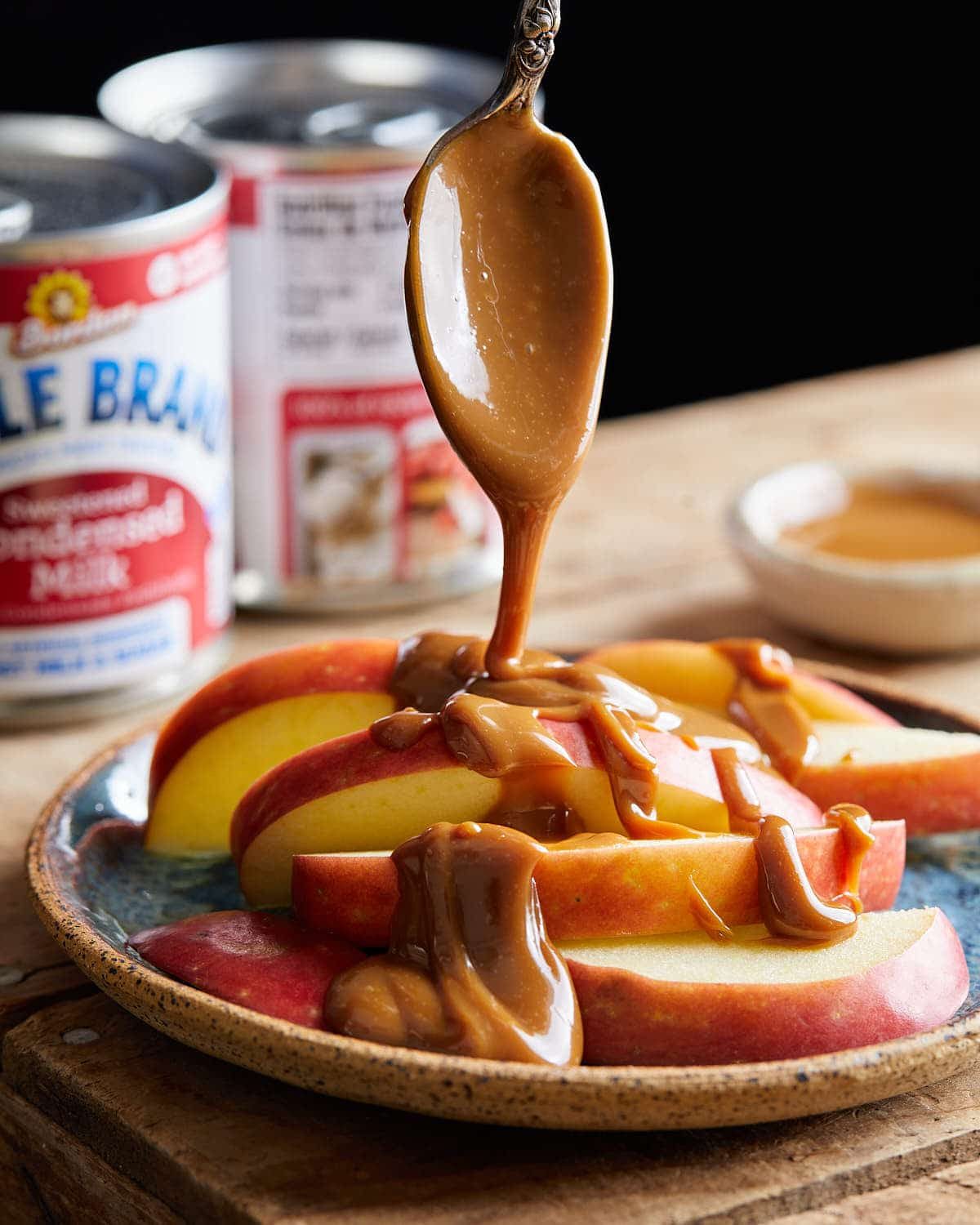 Condensed milk caramel being drizzled on to apple slices.