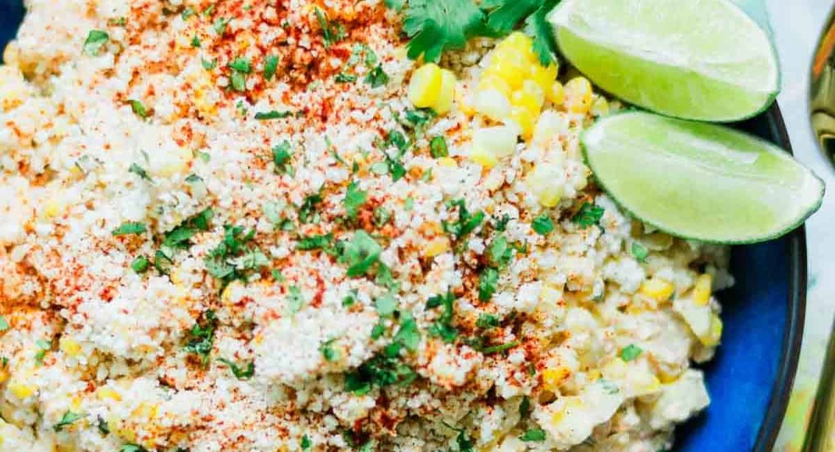 Overhead image of corn salad with two lime wedges and garnish.
