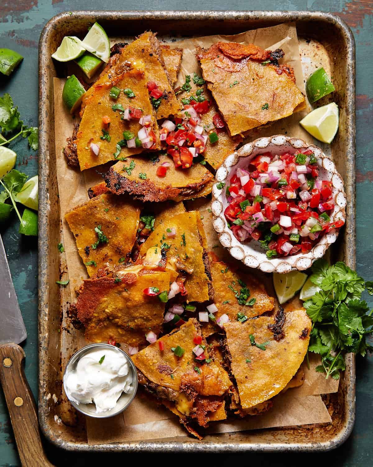 Shows finished corn tortilla quesadilla garnished with pico de gallo, cilantro, and sour crem