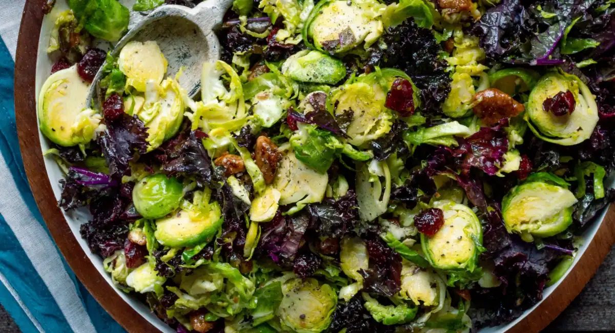 Overhead image of brussels sprouts salad with maple vinaigrette on white and brown dish.
