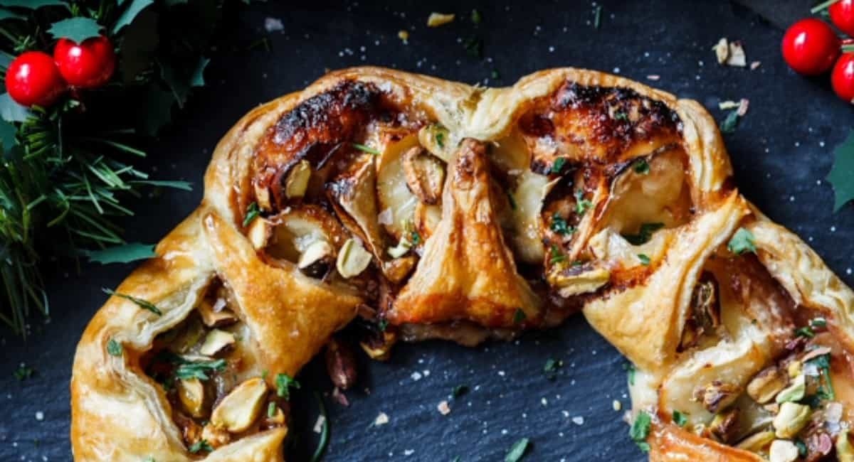 Overhead image of cranberry and brie puff pastry wreath with garnish.