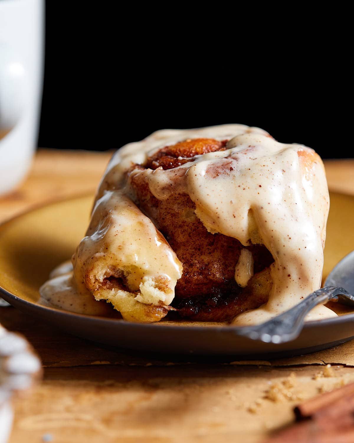 Up close side image of brown butter cinnamon rolls on brown plate.
