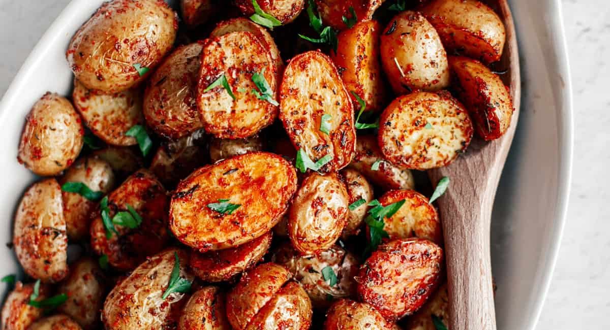 Overhead image of crispy oven-roasted mini potatoes with garnish.
