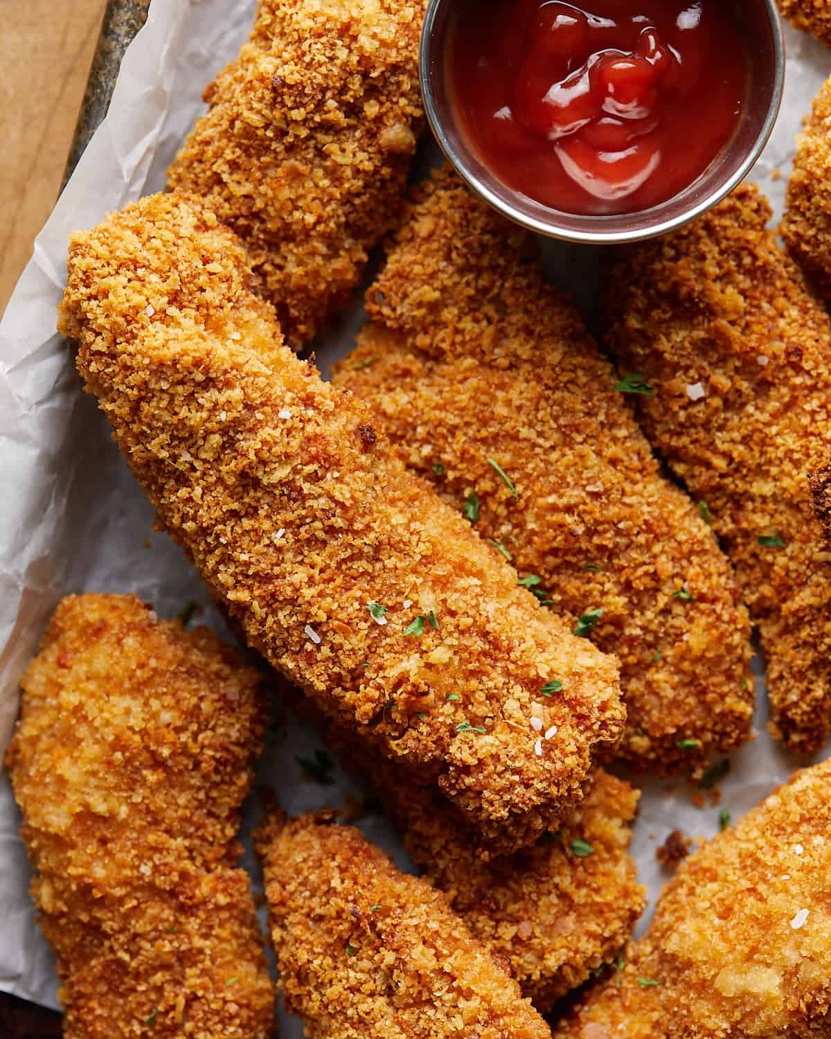 Close-up of golden panko-coated baked chicken tenders beside ketchup.