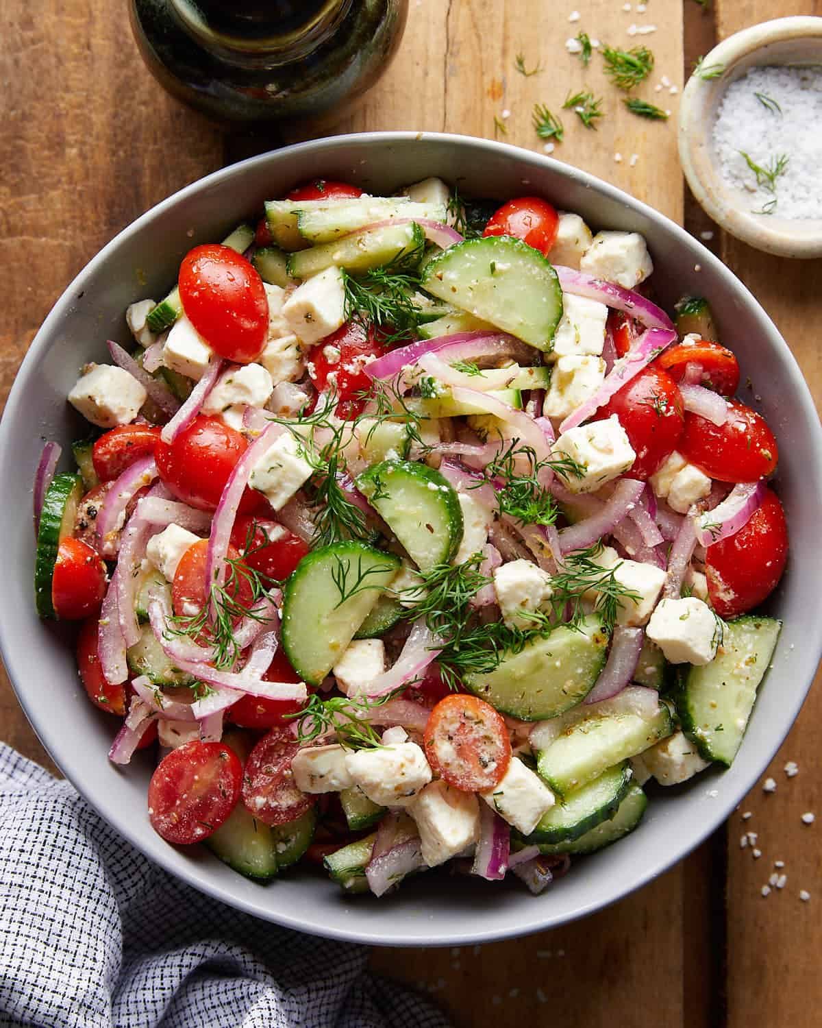 Overhead image of cucumber tomato and feta salad with garnish.
