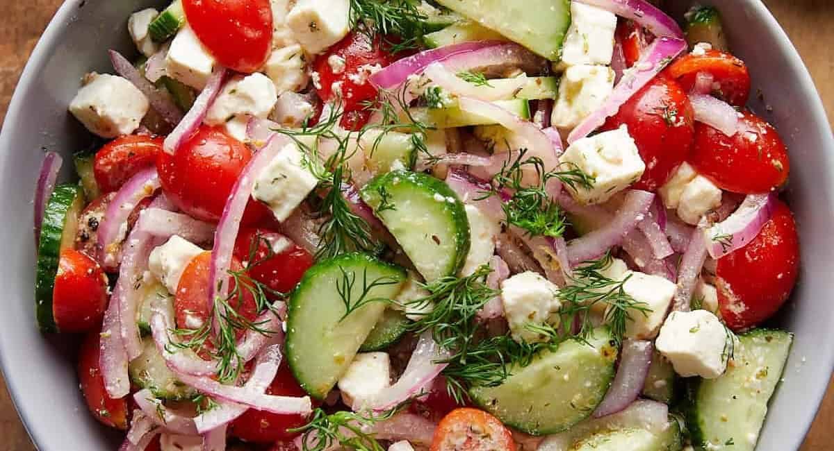 Overhead image of cucumber tomato and feta salad with garnish.