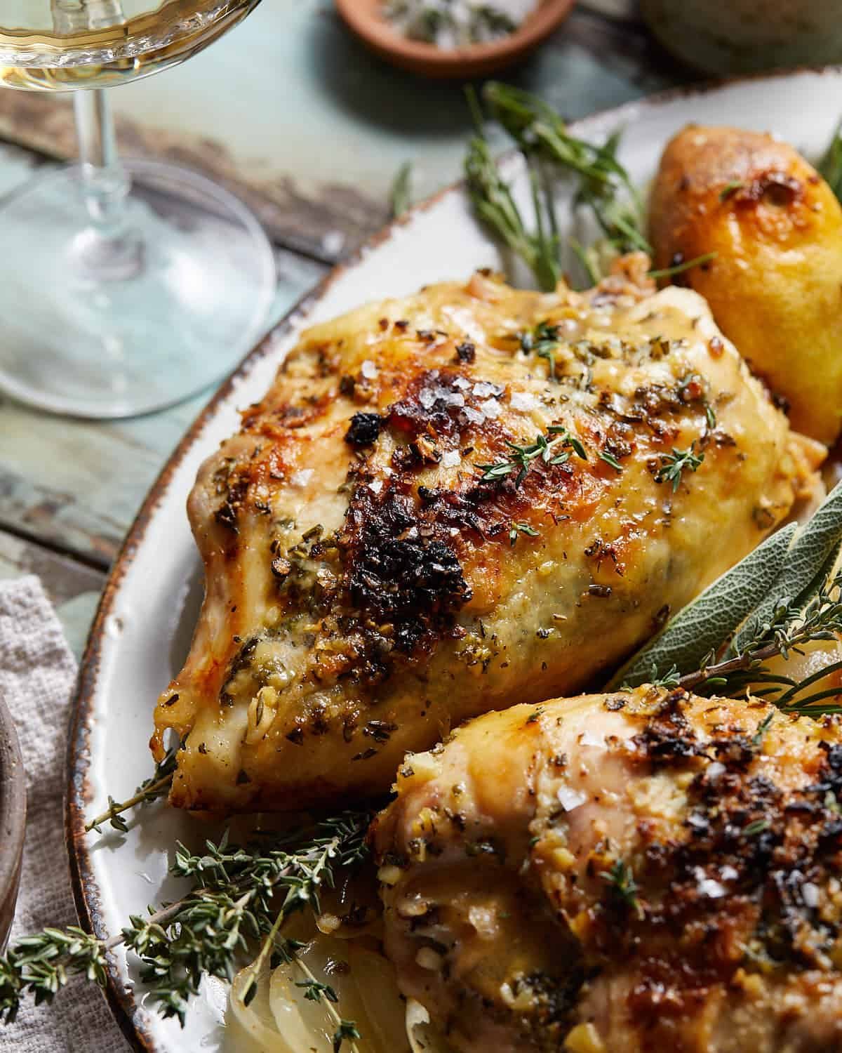 Dutch oven chicken breast on a white plate with garnishing.