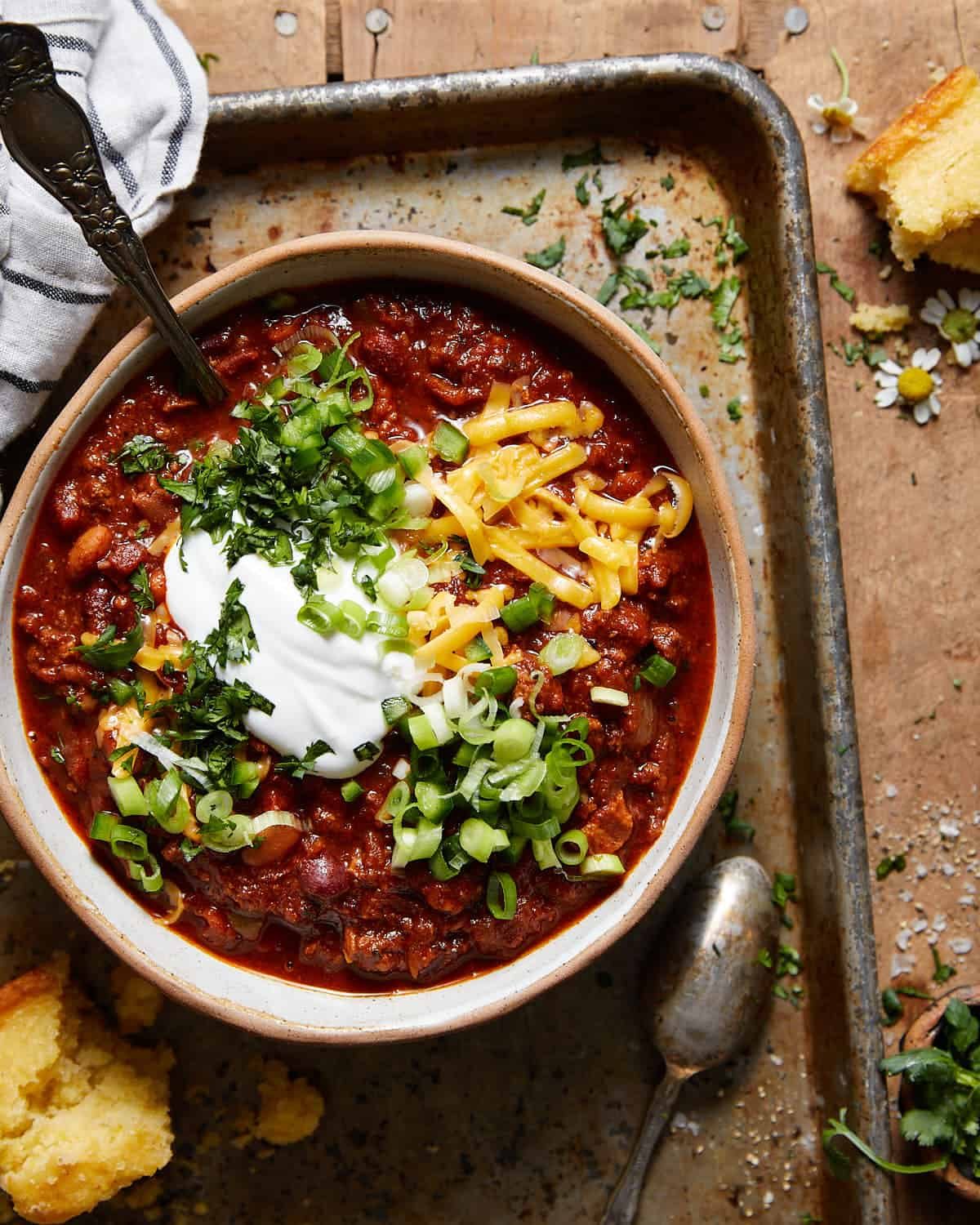 A finished bowl of Bri’s Dutch Oven Chili topped with cheddar, sour cream, green onions, and herbs