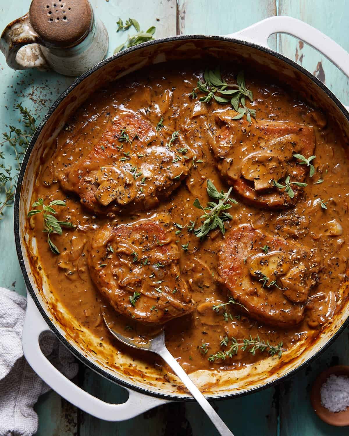 Overhead image of dutch oven pork chops in dutch oven with garnish.