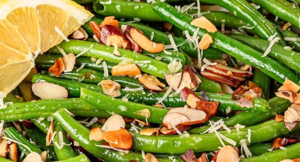 Up close image of green beans almondine with lemon wedge garnish.
