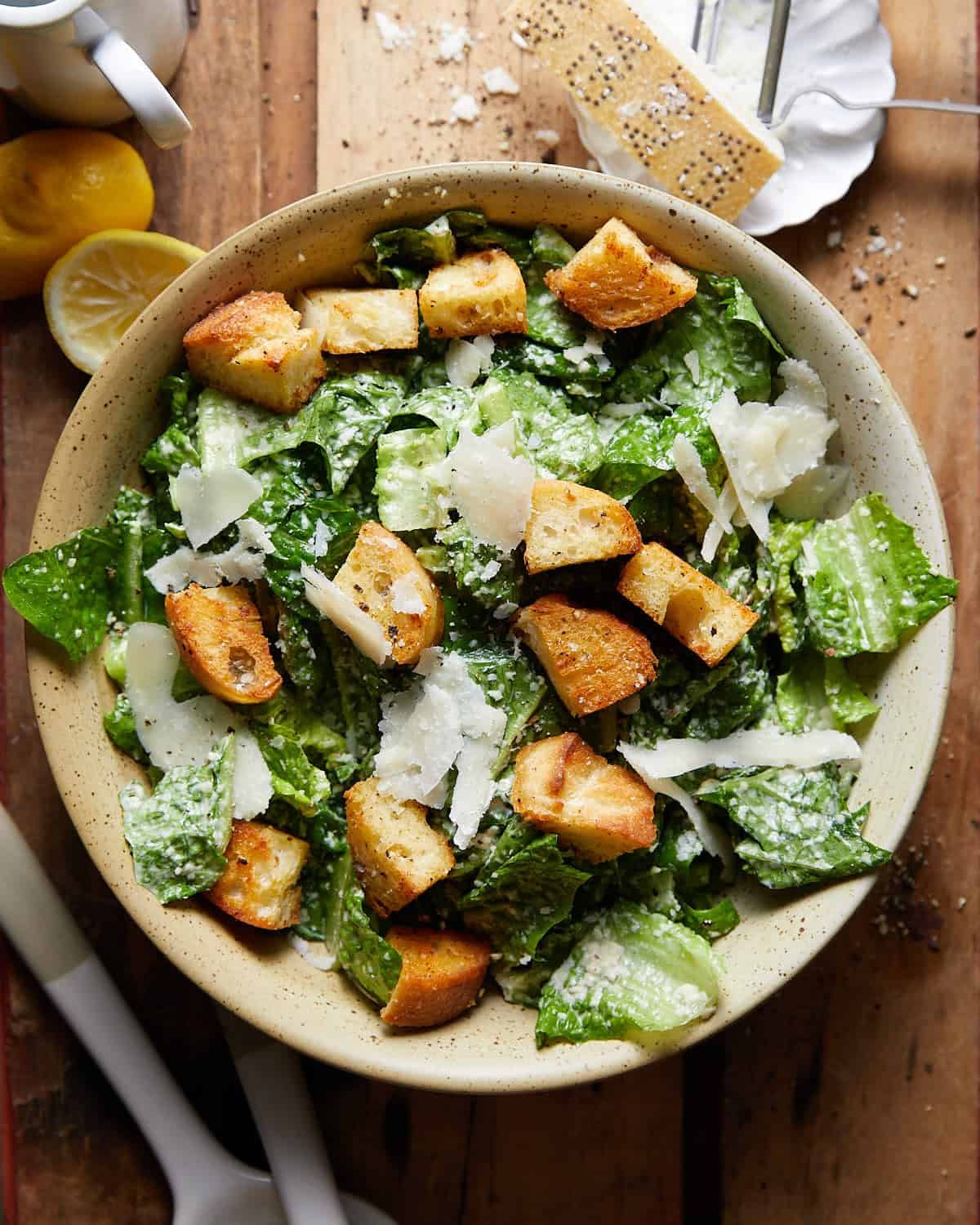 Overhead image of caesar salad in beige bowl.