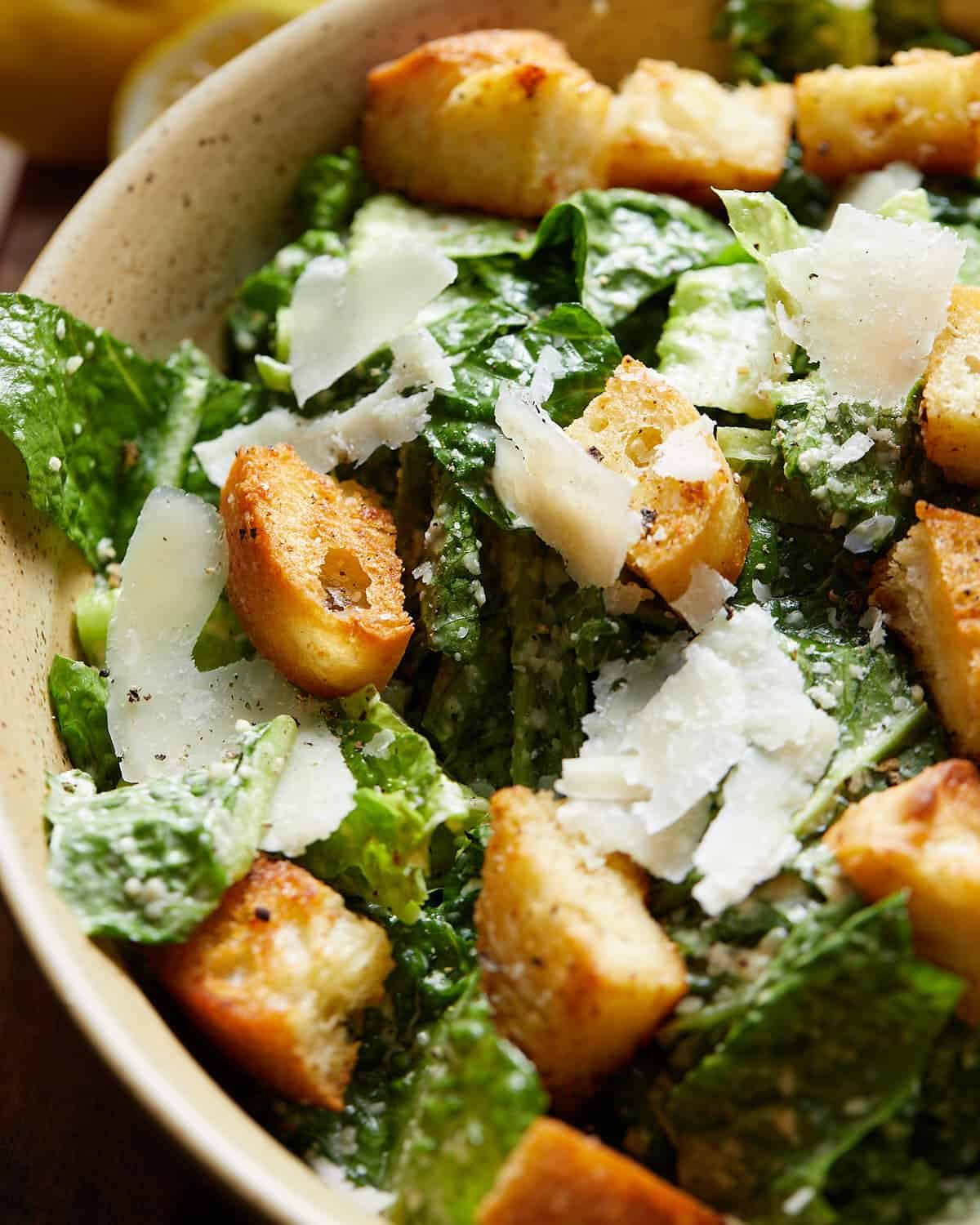 Up close image of caesar salad in beige bowl.