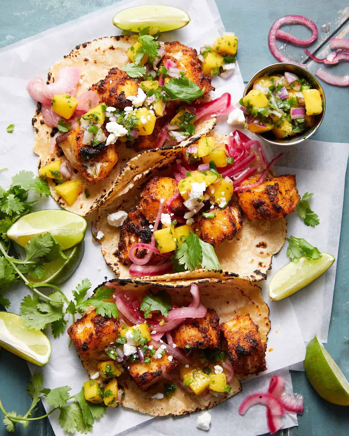 An overhead image of fish tacos with mango salsa and garnish.