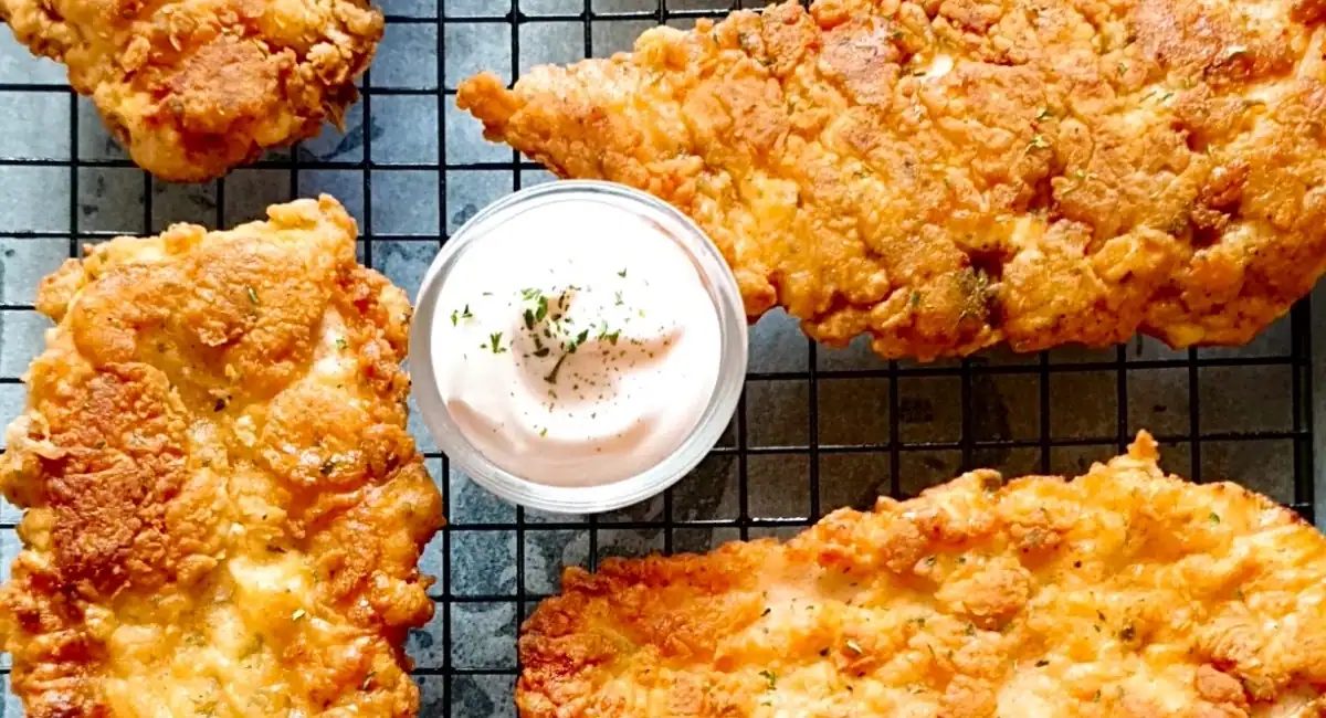 Overhead image of fried chicken breast on wire rack.