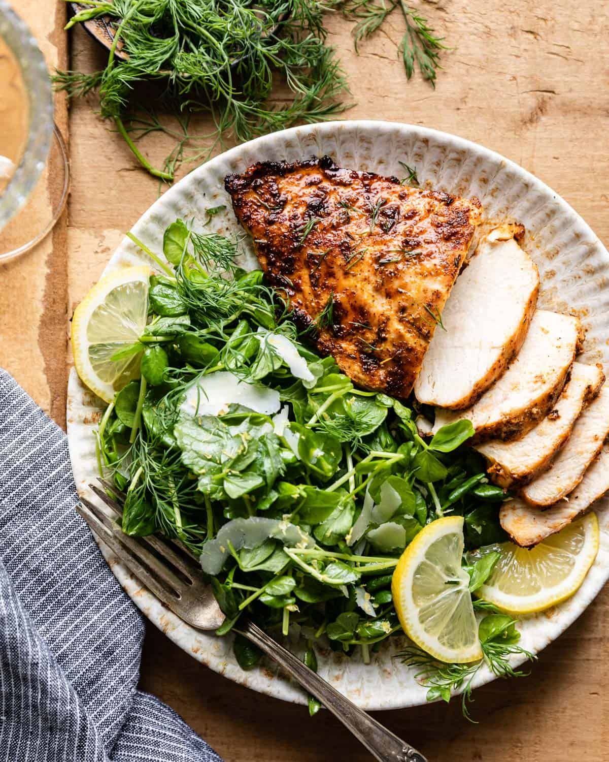 Overhead image of air fryer frozen chicken breasts with side salad.