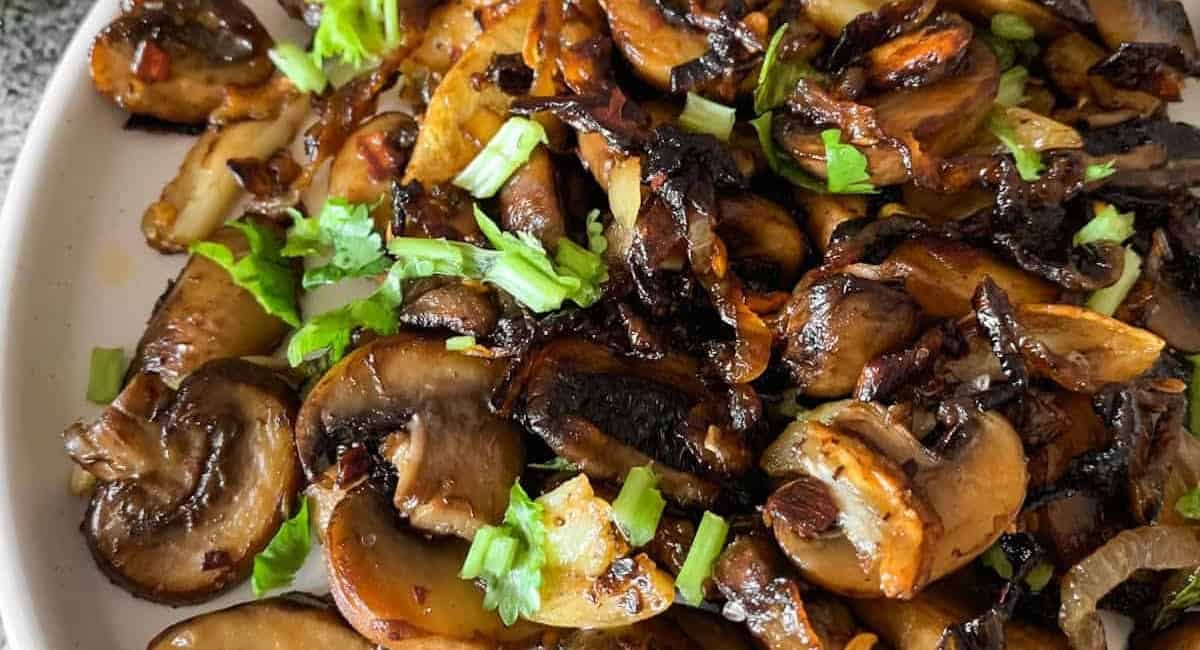 Overhead image of onions and mushrooms caramelized in garlic butter with garnish.