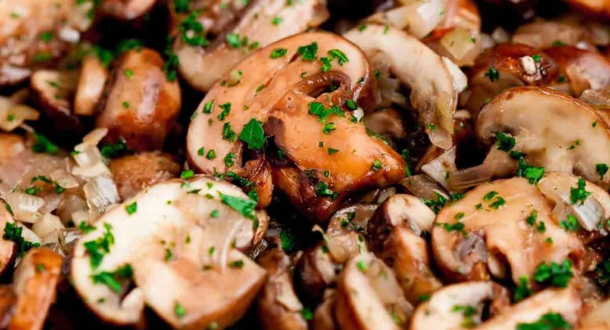 Up close image of garlic butter mushrooms with garnish.