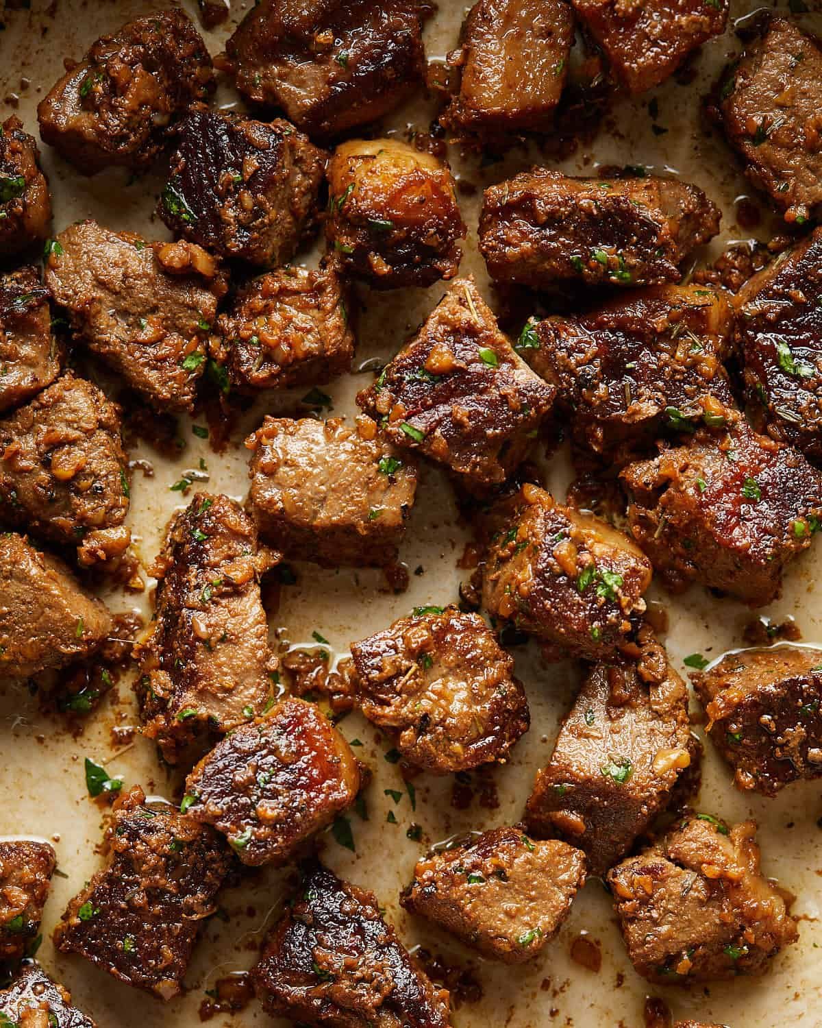 Up close overhead image of garlic butter steak bites with garnish.