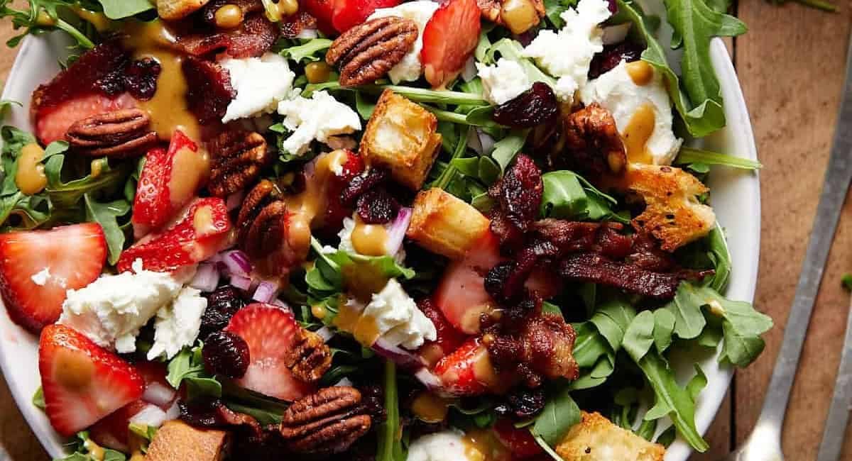 Overhead image of goat cheese salad with arugula on white dish.