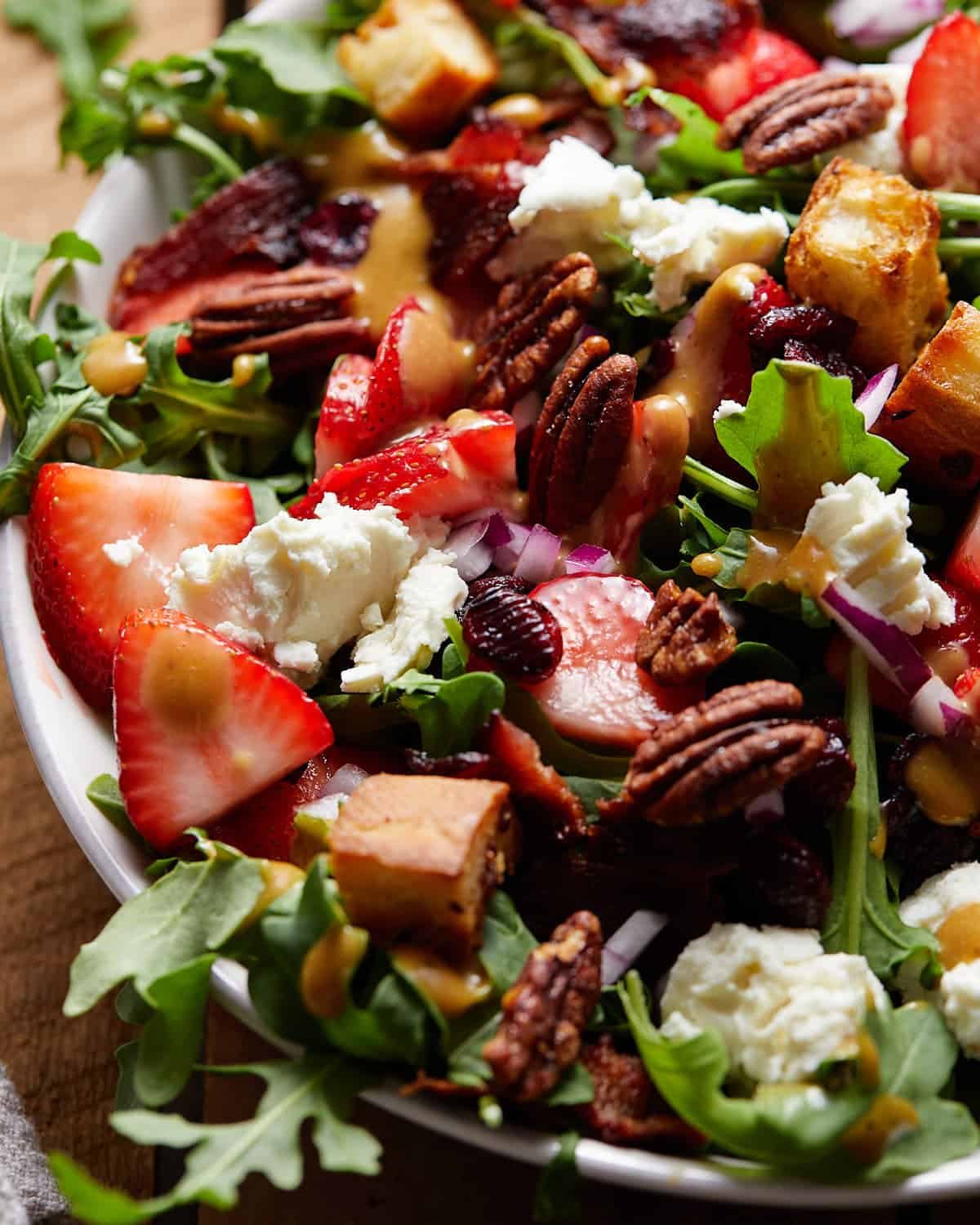 Goat cheese salad with arugula in a white bowl.
