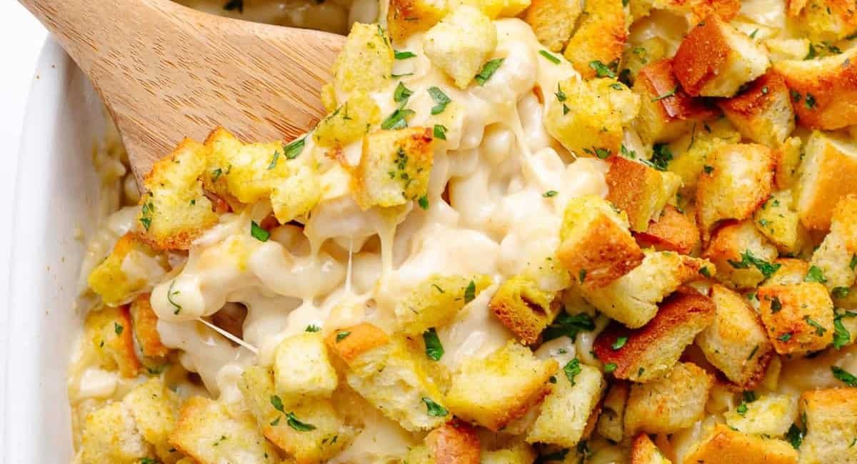 Overhead image of gouda mac and cheese with garnish and a wooden spoon.