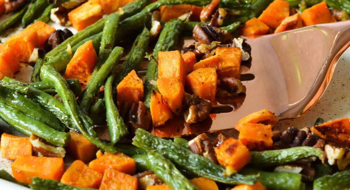 Up close image of green beans and sweet potatoes on sheet pan.