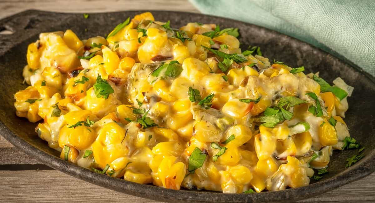 Up close image of Texas-style creamed corn with poblano peppers in cast iron skillet dish.