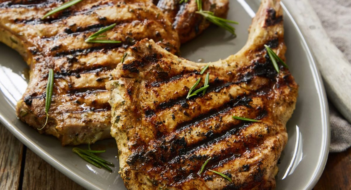 Overhead image of grilled pork chops with rosemary dijon marinade on white dish.