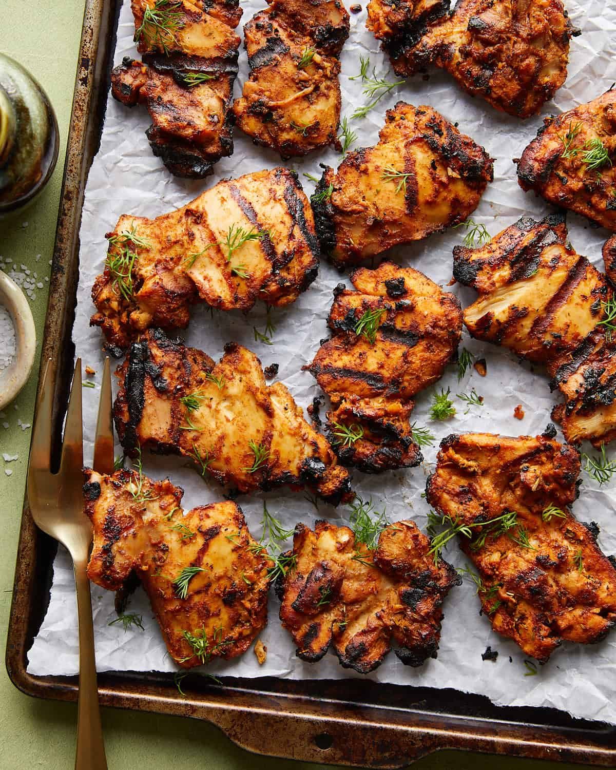 Overhead image of grilled boneless chicken thighs with garnish.
