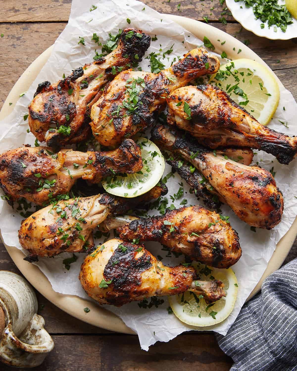 Overhead image of grilled chicken drumsticks with garnish.
