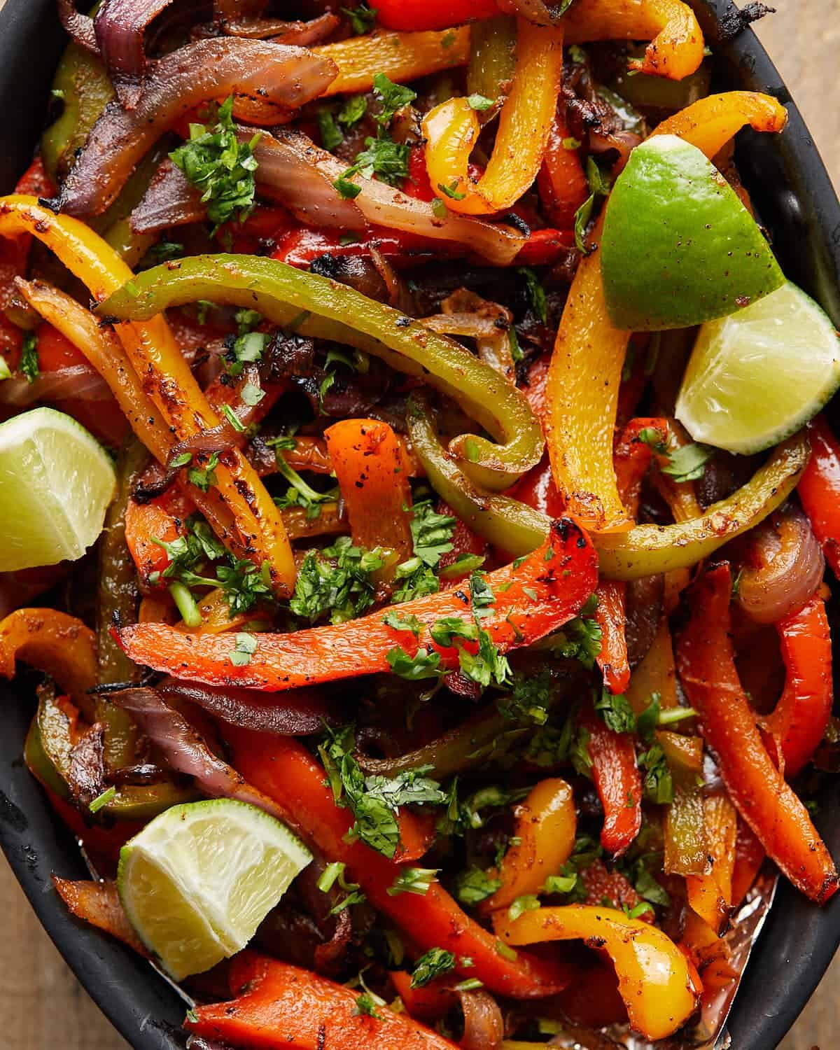 Overhead up close image of grilled peppers and onions with garnish.
