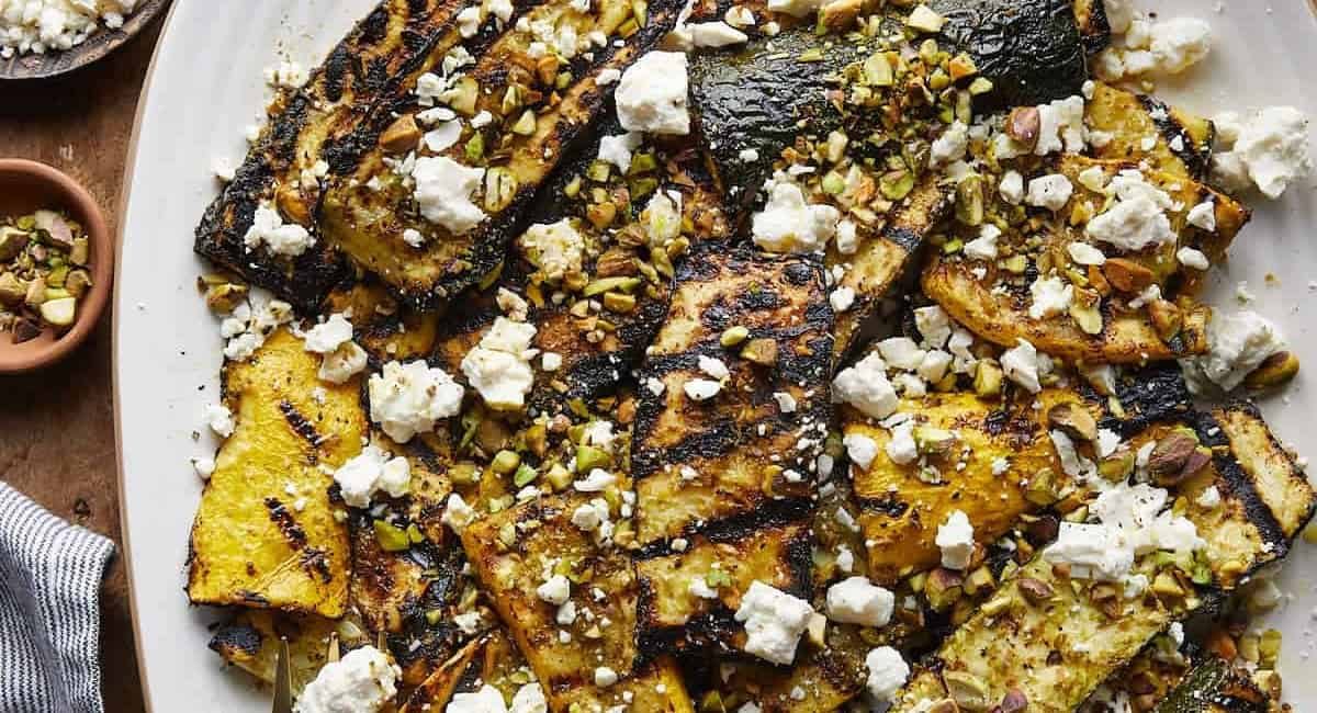 Overhead image of grilled zucchini and yellow squash with garnish.