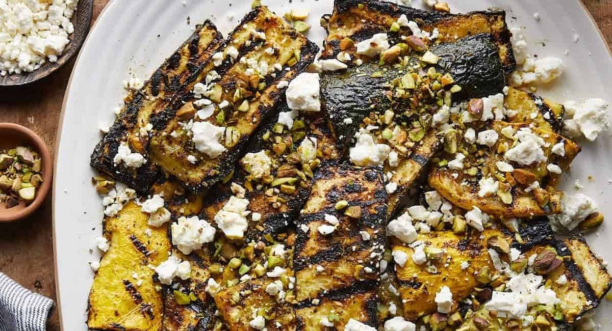 Overhead image of grilled zucchini and squash topped with feta and pistachios.