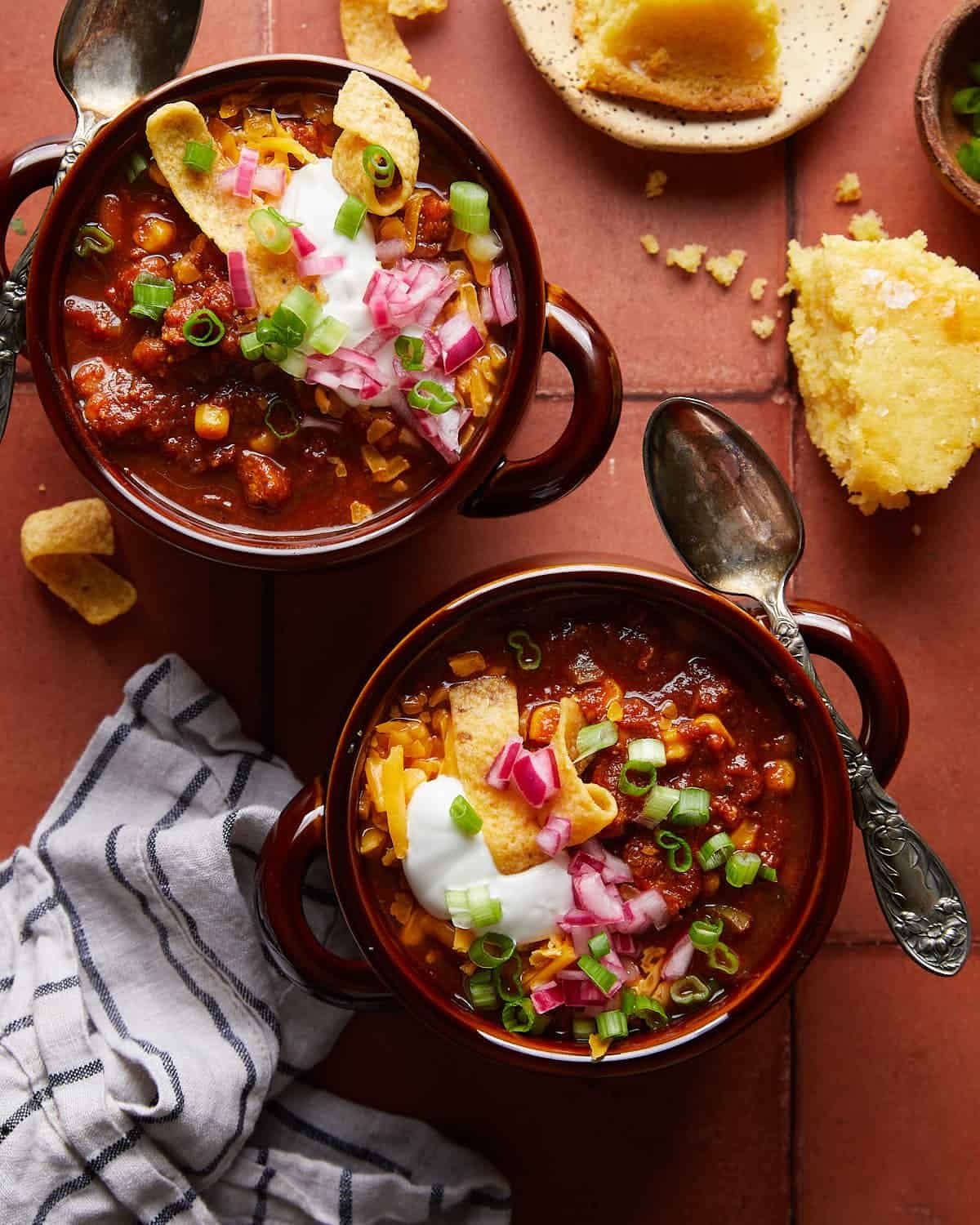 Overhead image of two bowls of ground chicken chili with garnish.