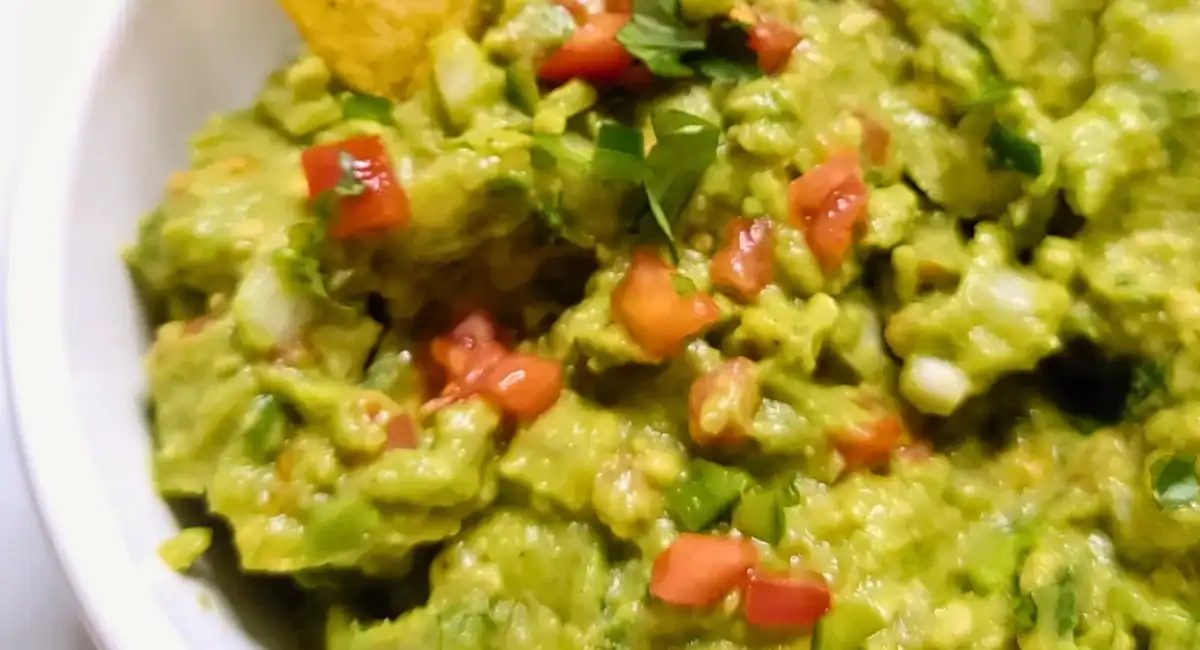Overhead up close image of guacamole in white dish.