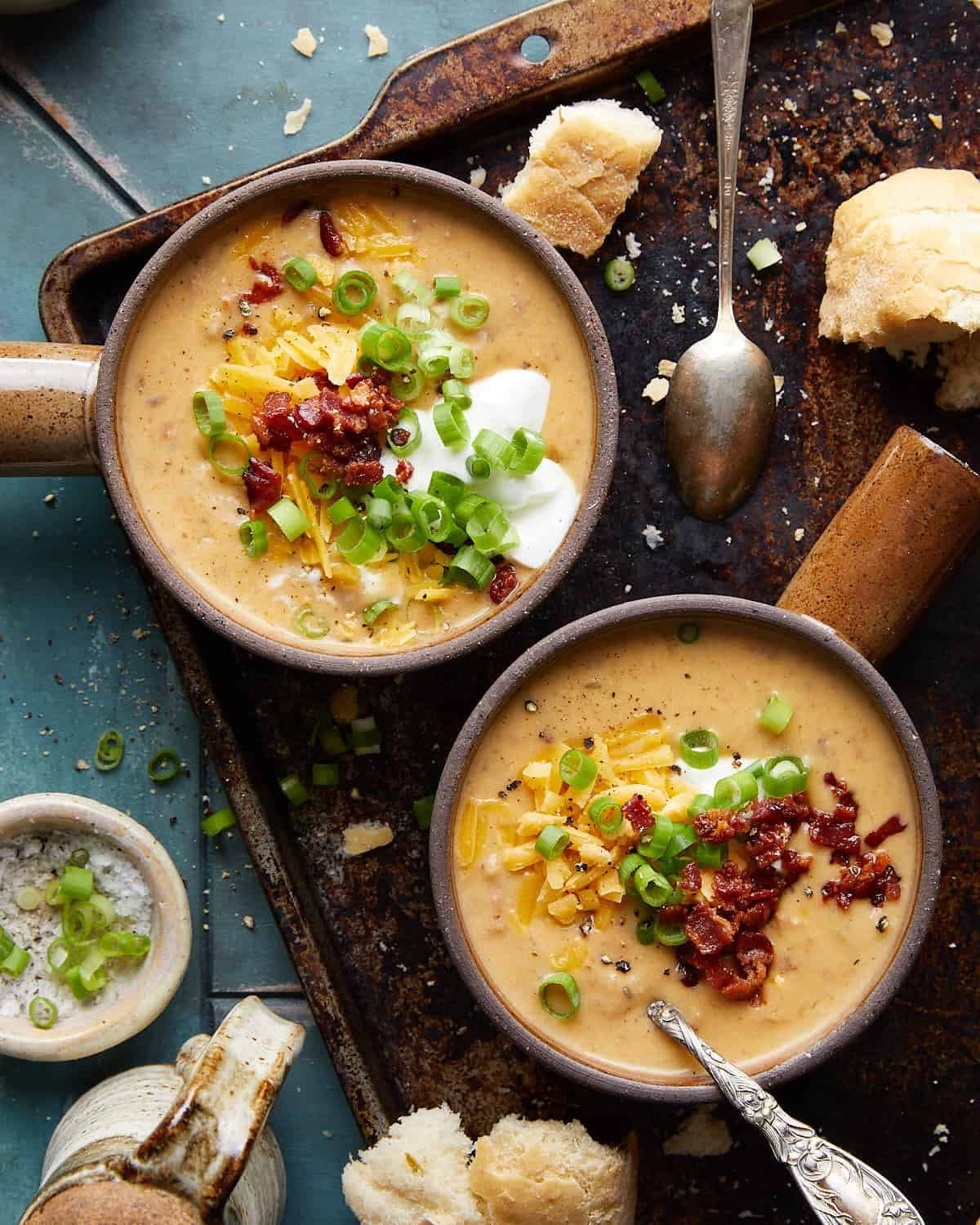 Overhead image of crockpot potato soup with hash browns in two soup bowls with garnish.