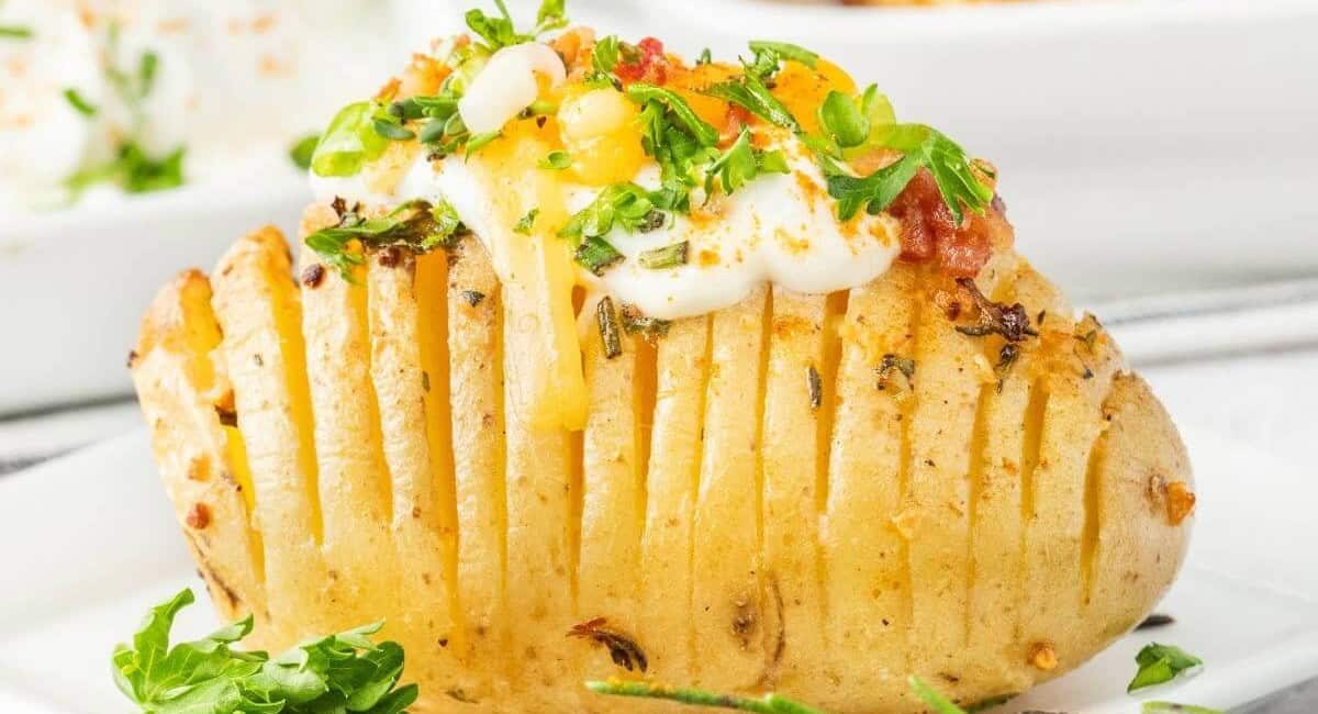 Up close image of air fryer hasselback potato with garnish and toppings.