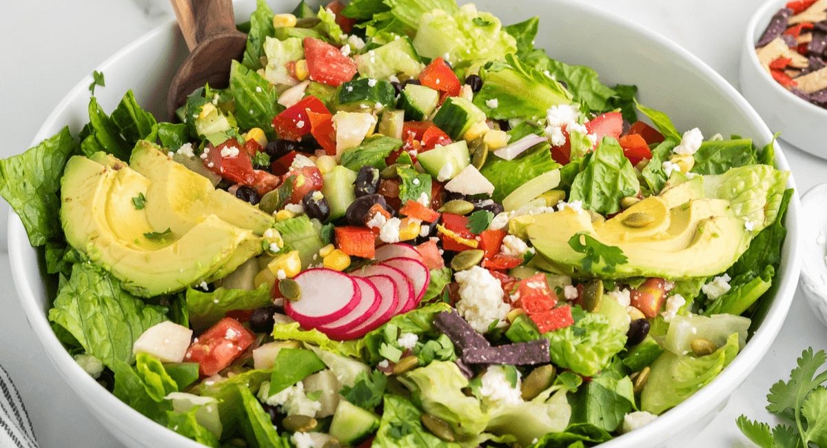 Overhead image of healthy Mexican chopped slad with lime dressing in a white bowl.