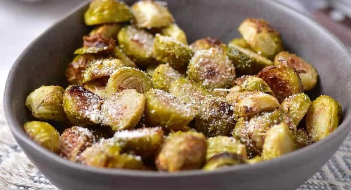 Up close image of oven roasted brussels sprouts in grey bowl.