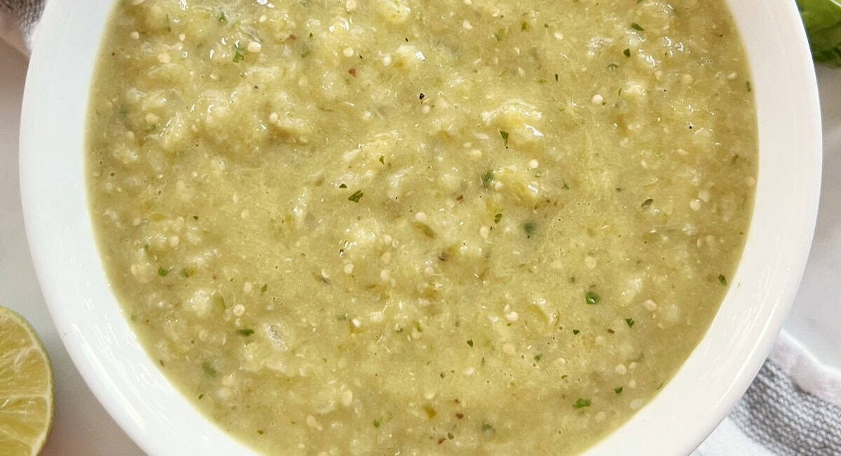 Overhead image of homemade roasted tomatillo salsa in white bowl.