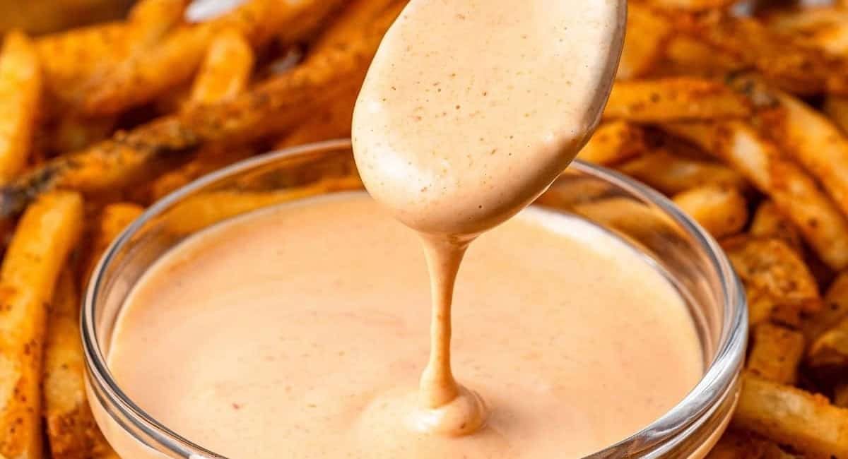 Up close image of sriracha aioli with fries in the background.