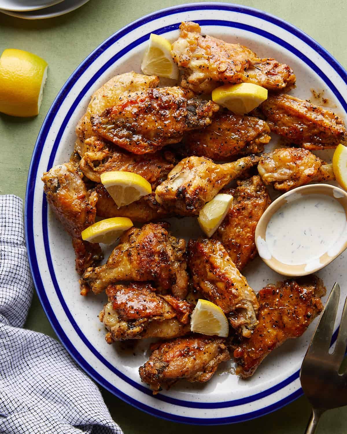 Overhead image of honey lemon pepper wings with lemon garnish and a side of ranch dressing.