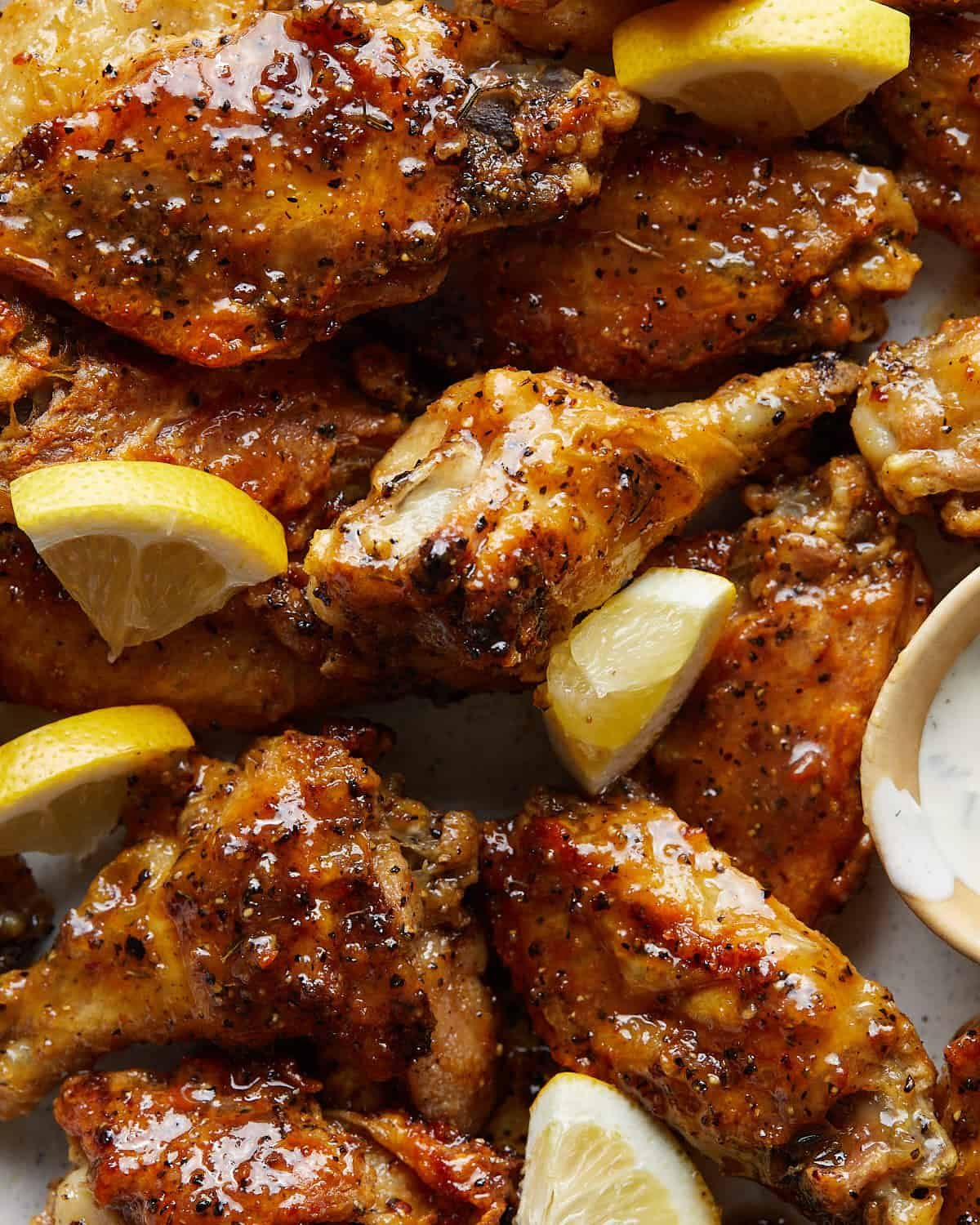 Up close image of honey lemon pepper wings with lemon garnish.