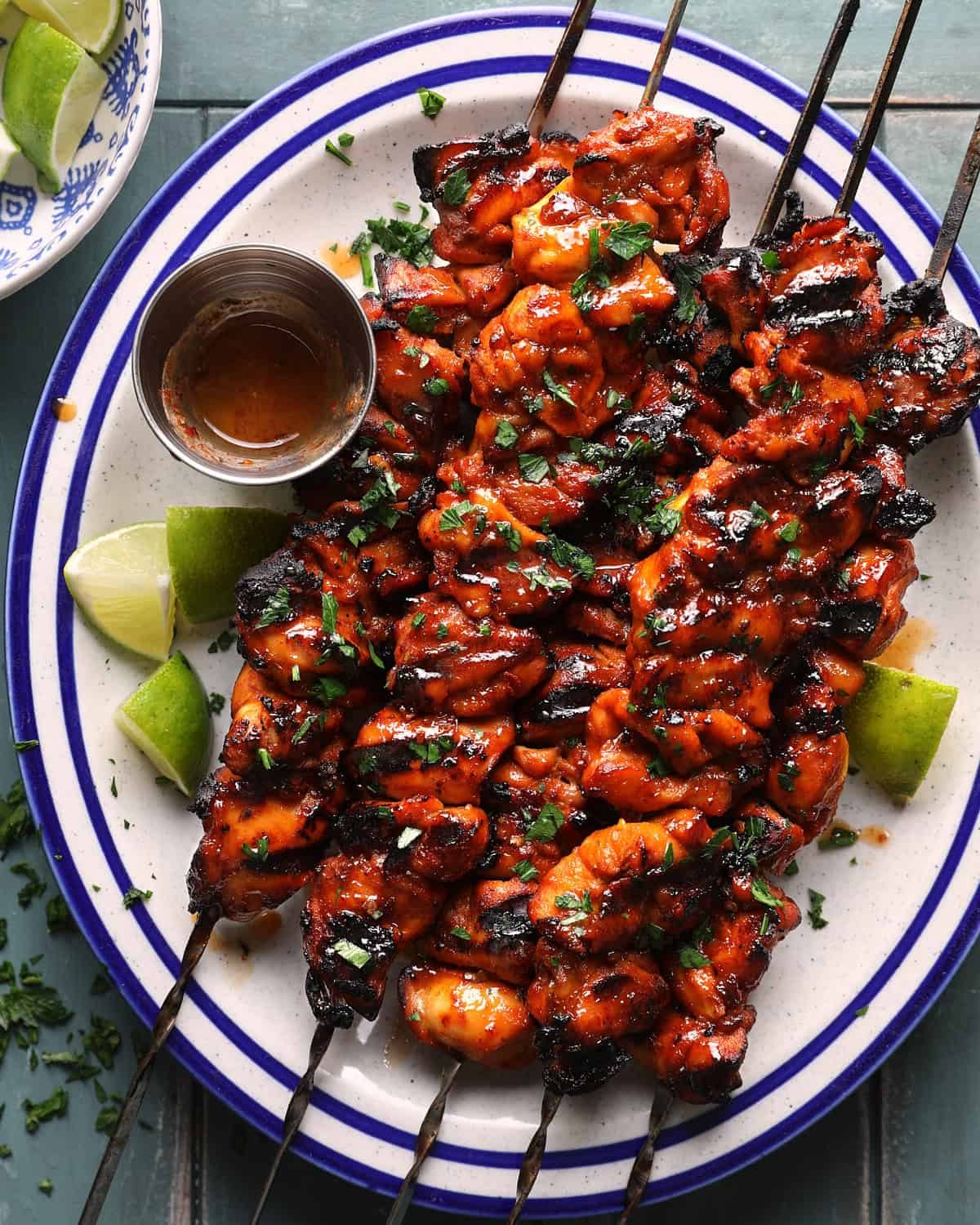 Grilled chipotle lime chicken skewers served with lime wedges and extra hot honey sauce.