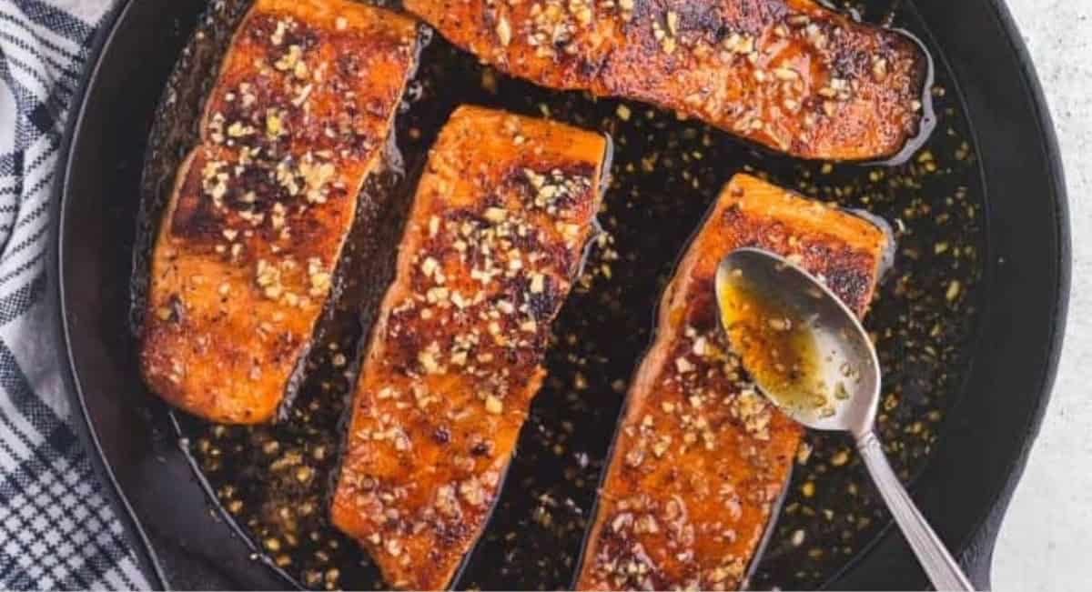 Overhead image of hot honey salmon in cast iron skillet with garnish.