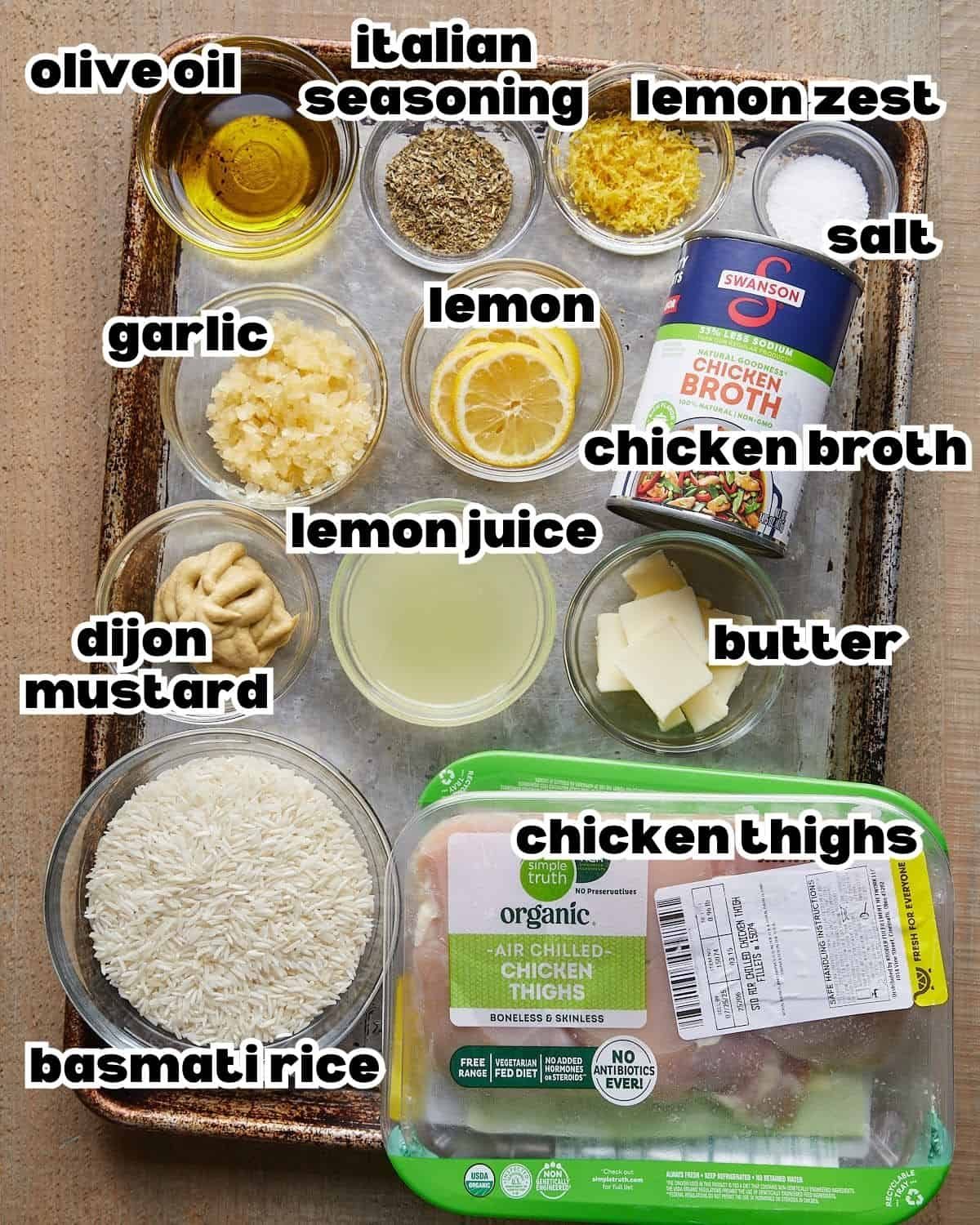 Labeled ingredients for baked lemon chicken and rice, including chicken thighs, basmati rice, broth, lemons, garlic, Dijon, butter, olive oil, and seasonings.