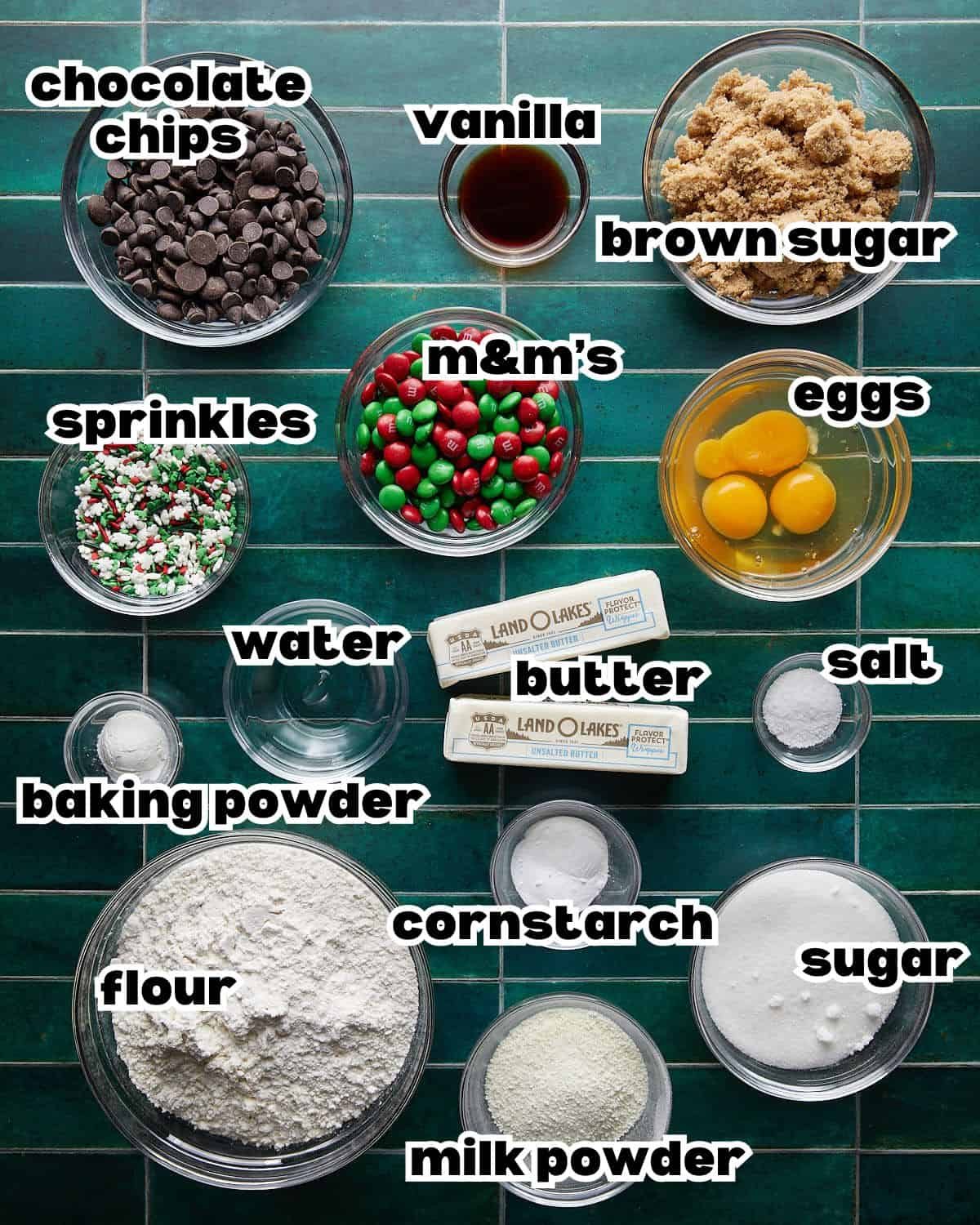 Overhead image of ingredients needed to make Christmas chocolate chip cookies, including butter, sugar, flour, chocolate chips, eggs, and baking essentials arranged on a countertop.